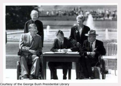 photo of the ceremonial signing of the americans with disabilities act by president george. h. w. bush. he is joined by texan disability advocate justin dart.